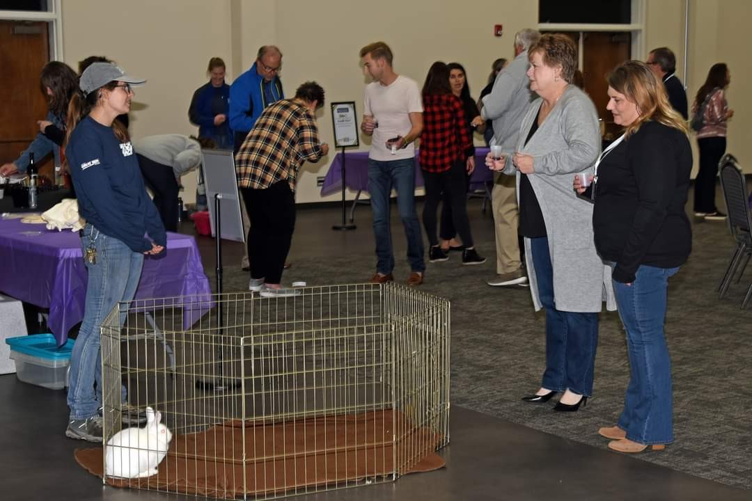 A group of people gathered around a cage containing a dog, observing and interacting with it