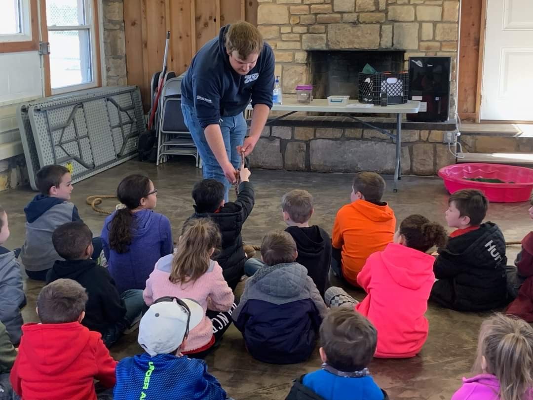 A man teaches children about animals in a classroom setting, engaging them with visual aids and interactive materials